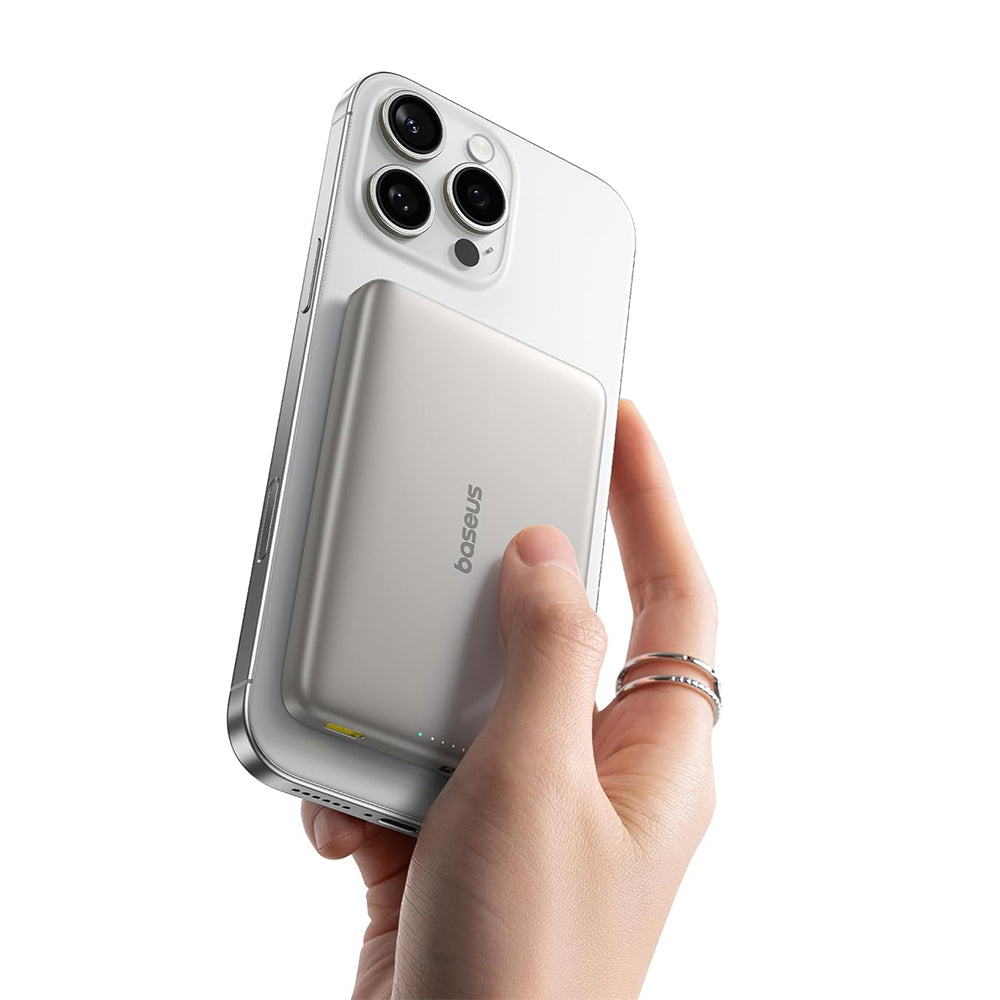 Hand holding a smartphone with a wireless charging power bank, brand 'baseus' visible
