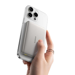 Hand holding a smartphone with a wireless charging power bank, brand 'baseus' visible